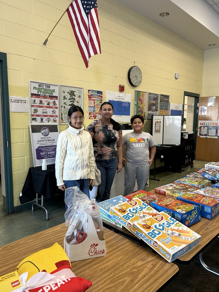 Kids standing in behind a table filled with games.