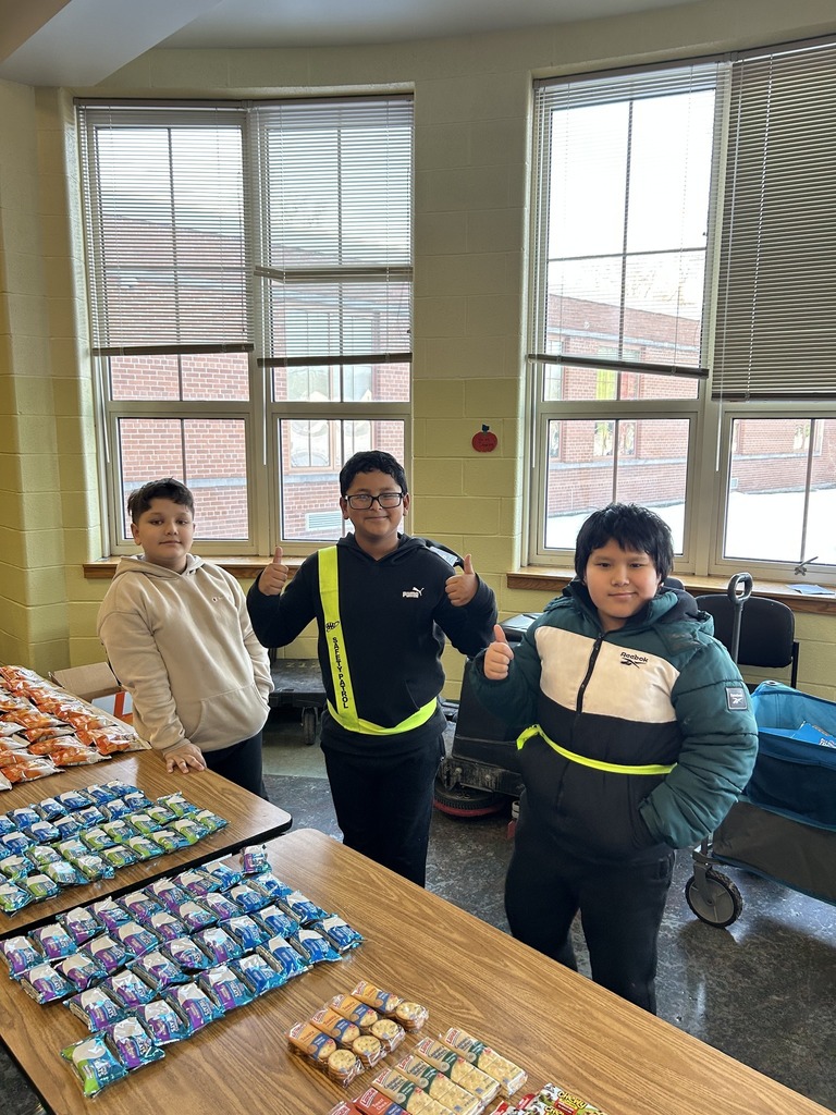 Kids standing behind a table filled with snacks.