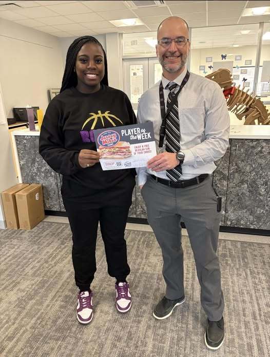 A young girl in a black outfit is standing next to a man in a striped tie while they both hold a certificate.