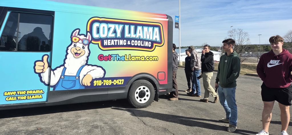 Five people are standing next to a blue and rainbow-colored van with a cartoon character on it.