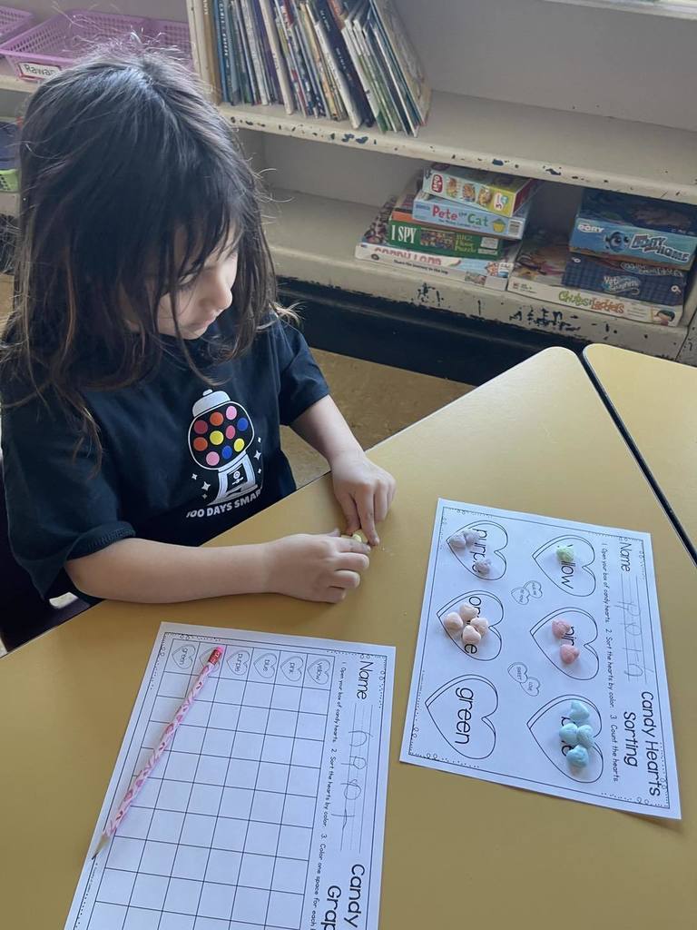 Student doing an activity in class, using candy and paper. 