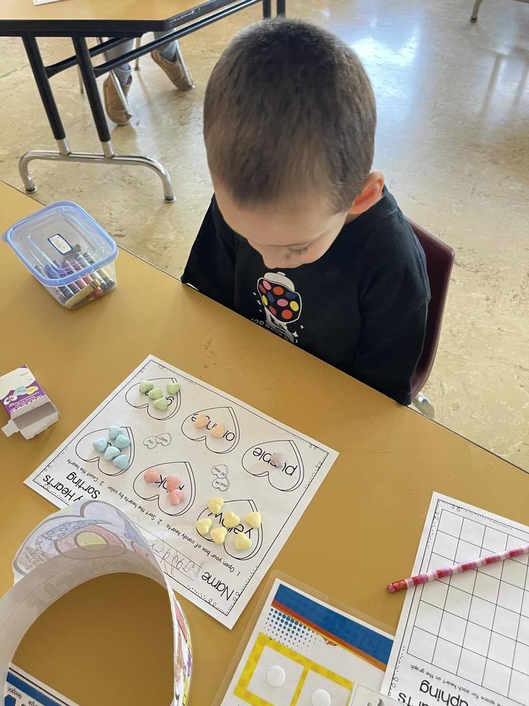 Student doing an activity in class, using candy and paper. 