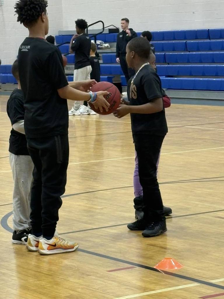 Students wearing black shirts are playing basketball. 