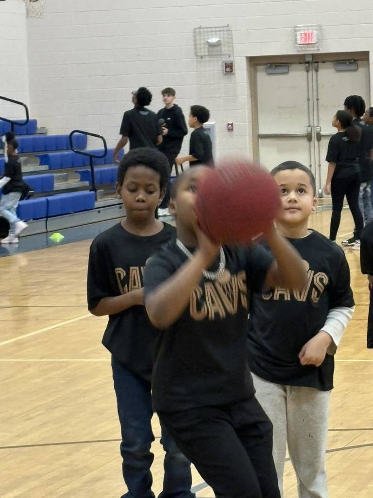Students wearing black shirts are playing basketball. 