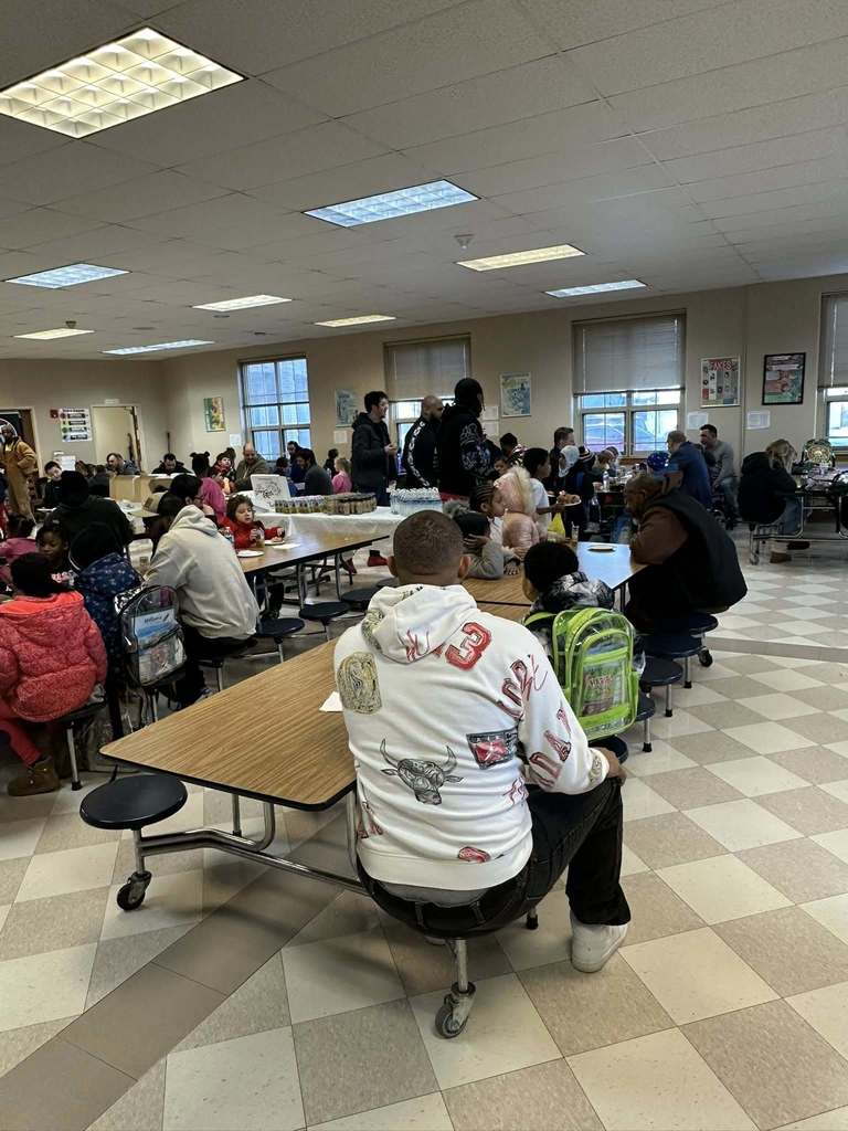 People sitting at tables in a school cafeteria. 