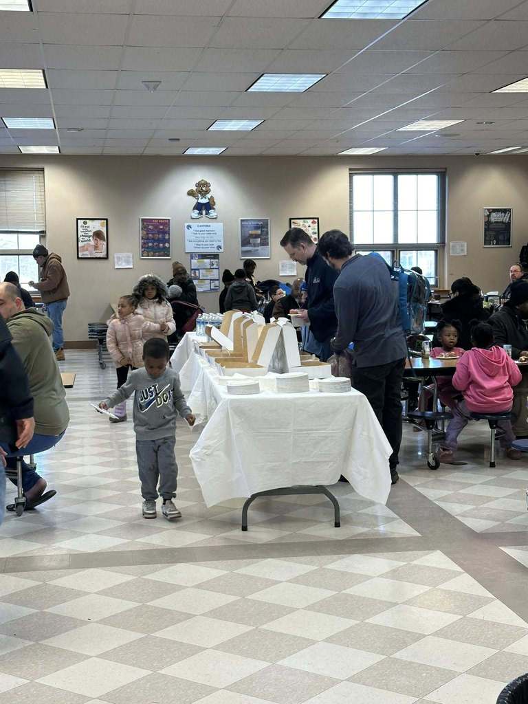 People sitting at tables in a school cafeteria. 