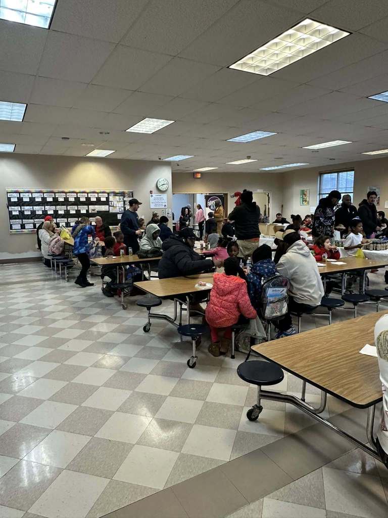 People sitting at tables in a school cafeteria. 