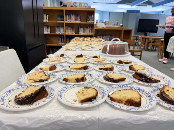Cake served on plates and is placed on a long table. 