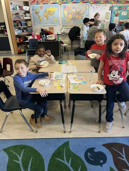 Students sitting at their tables in class and smiling. 