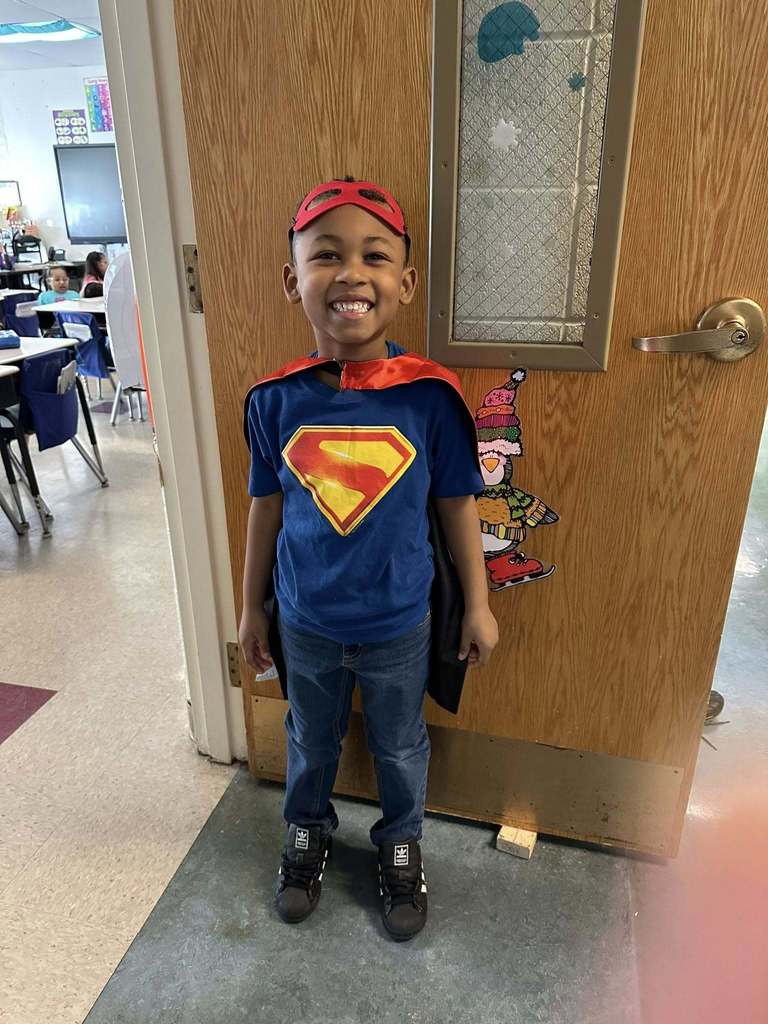A young boy dressed like superman. 