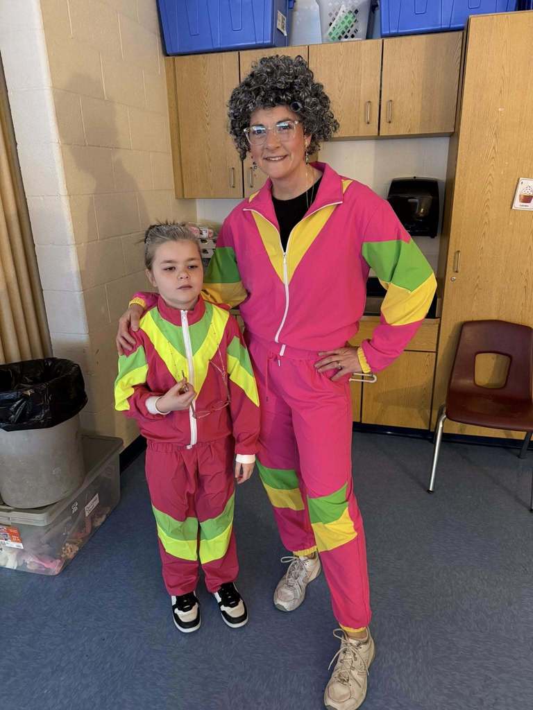 An adult and student dressed like old women and bright neon clothing. 