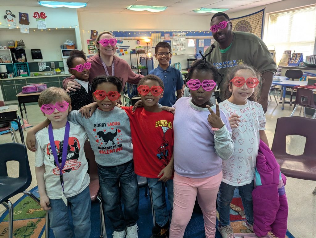 A group of students and adults and they are all wearing heart glasses. 