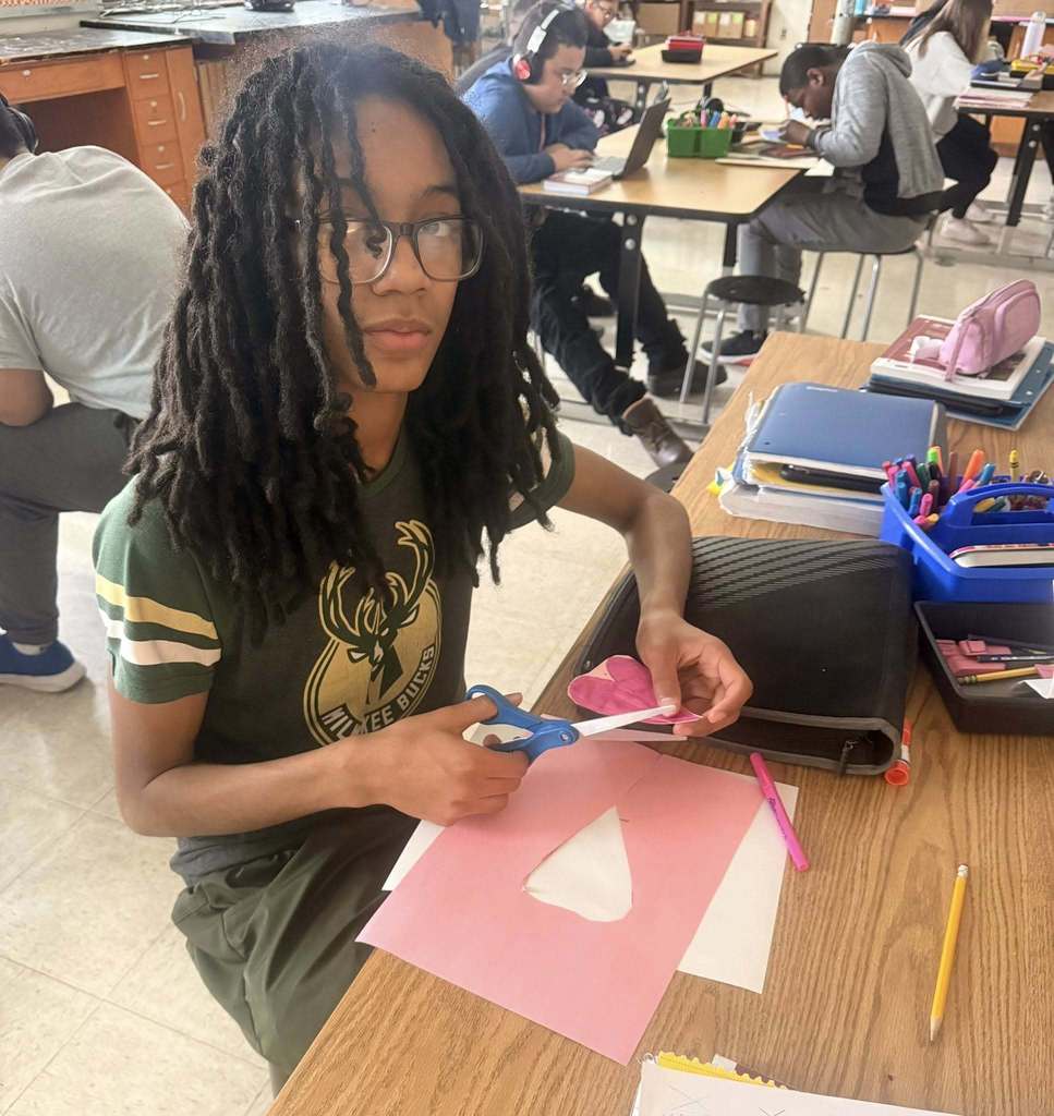 Student cutting out a pink heart.