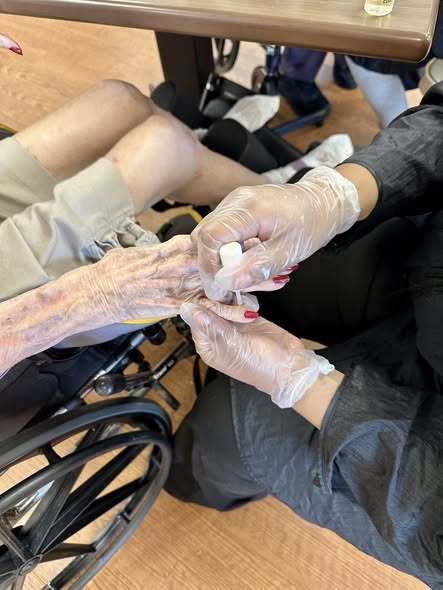 A hand with gloves painting another individuals nails.