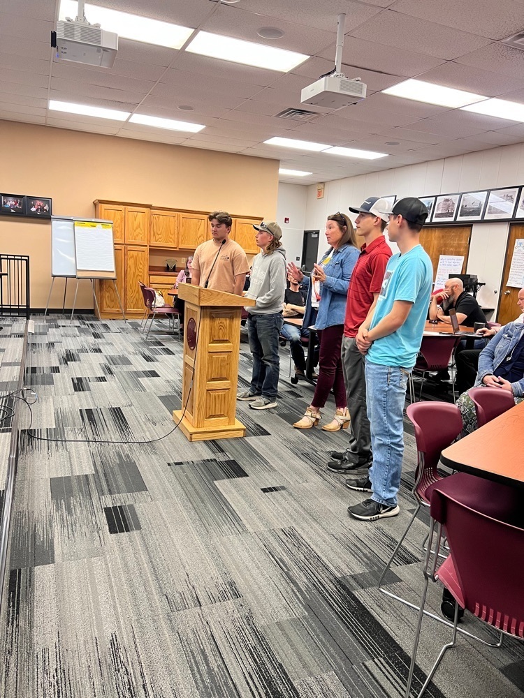 students and a teacher presenting to the board. 
