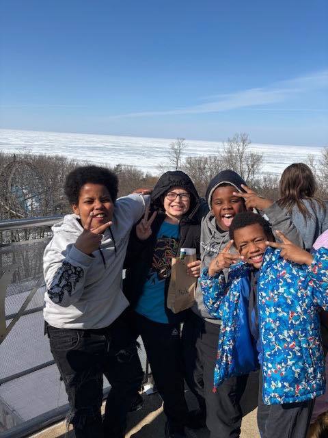 A group of students smiling outside with a frozen lake behind them. 