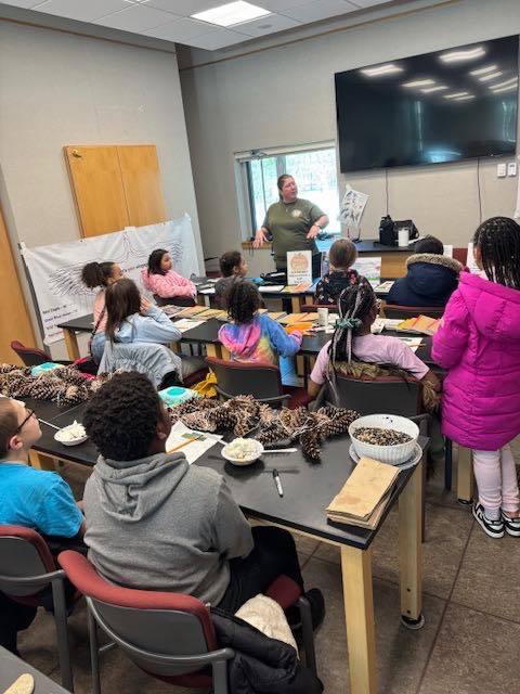 Kids listening to a women speak in a classroom. 