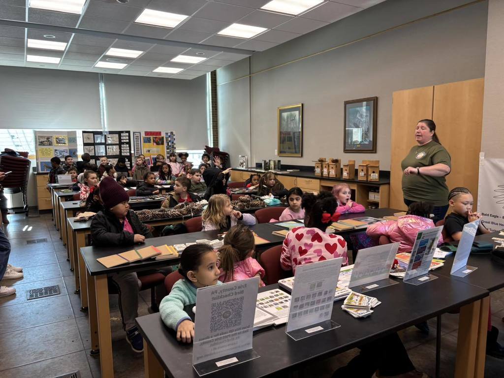 Kids listening to a women speak in a classroom. 
