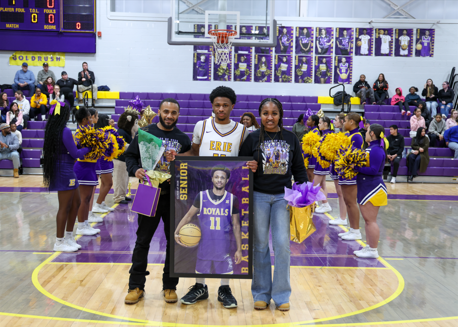 A young man holding up a poster of himself and his family next to him also holding hist poster.