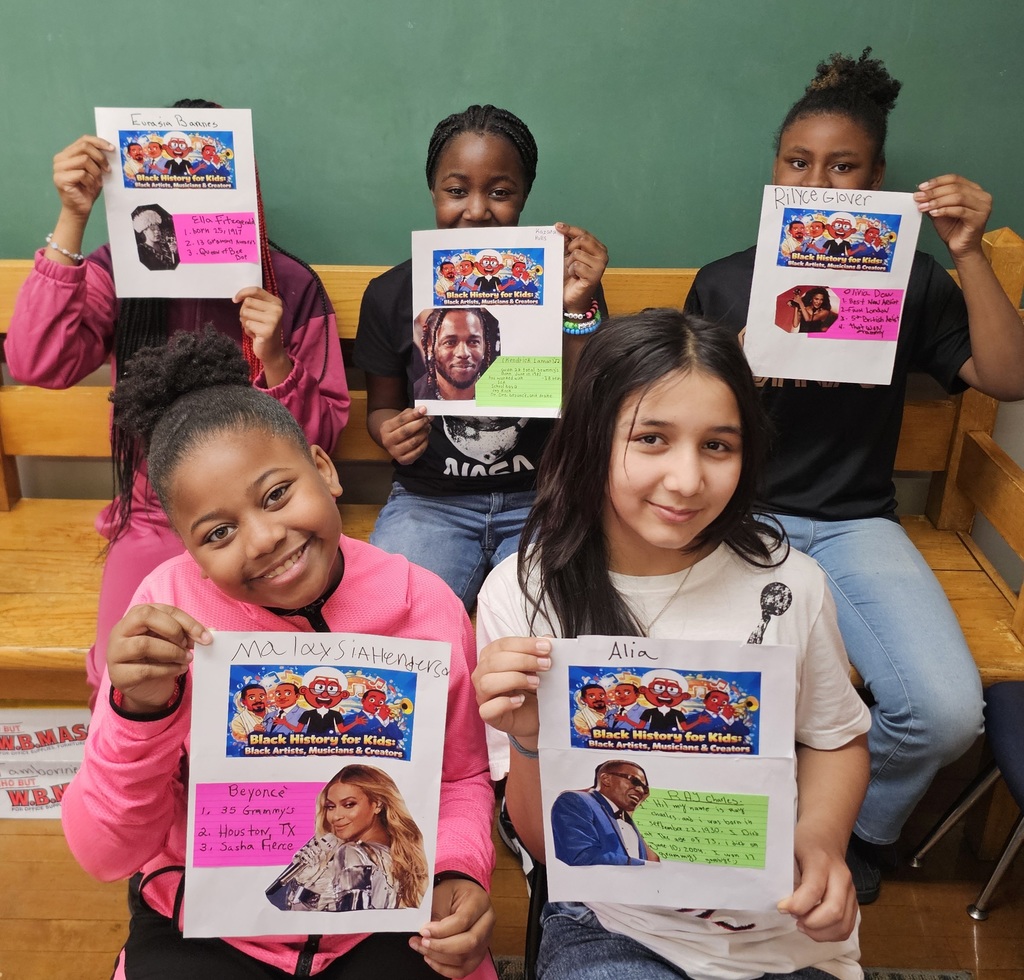 Students holding posters with artists on them.