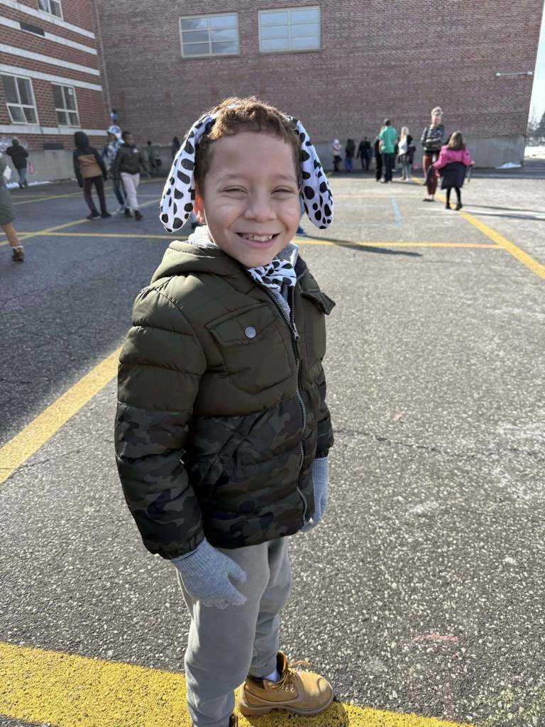 Young boy wearing a jacket outside and Dalmatian ears.