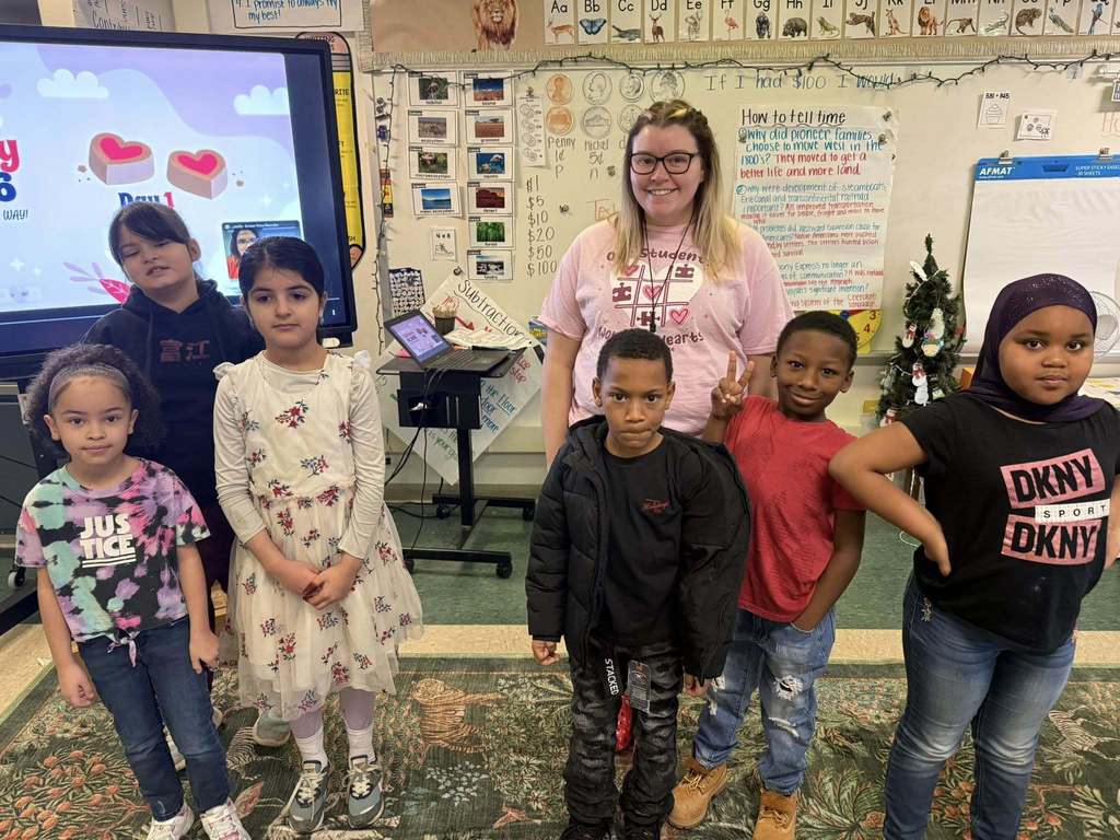 Group of students and teacher smiling in class. 