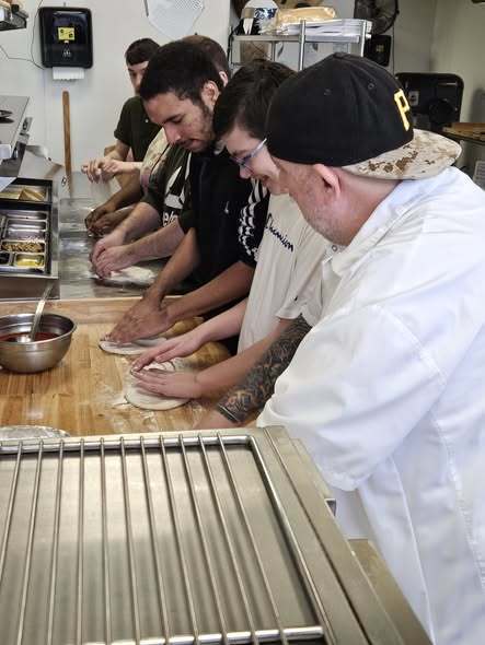 Students learning how to make fresh pizza.