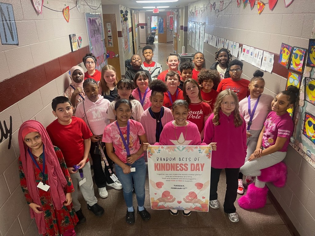Students wearing red and pink for Random Acts of Kindness Day as they hold the poster for the day. 