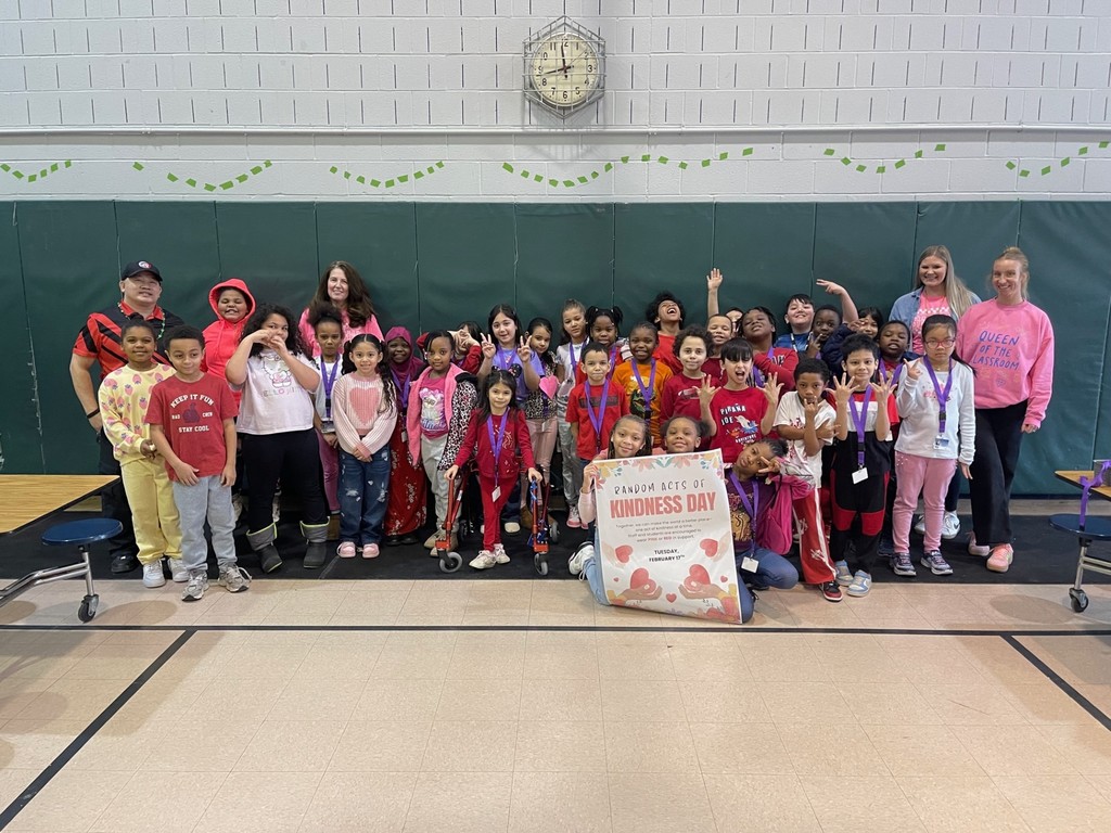 Students and staff wearing red and pink for Random Acts of Kindness Day as they hold the poster for the day. 