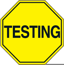 Octagon sign with black text "TESTING" on a bright yellow background. Black border around the sign.
