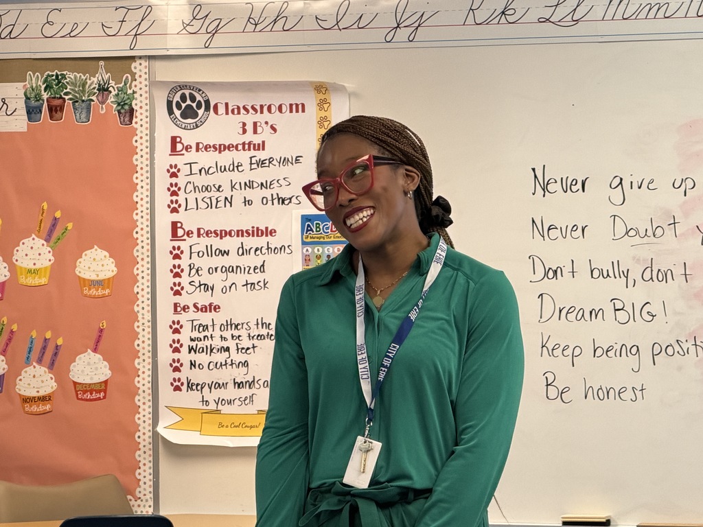 A women in a green top and red glasses smiling.