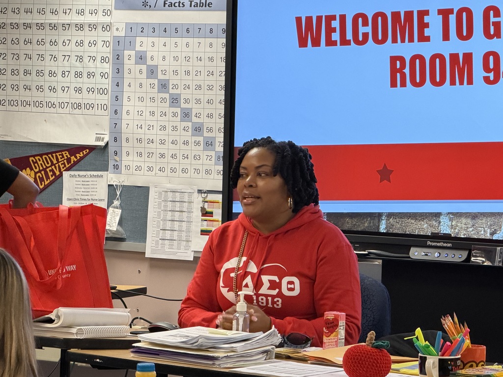 A women in a red hoodie speaking to a classroom.