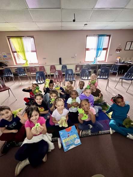 Students sitting in class while they hold green frogs. 