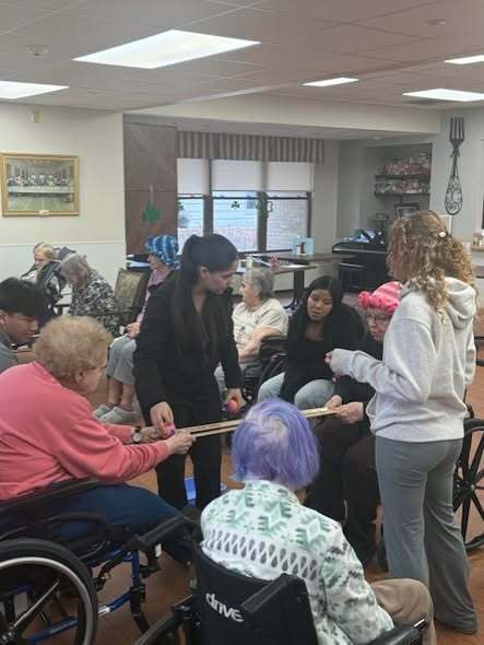 Students interacting with elderly individuals in a nursing home.