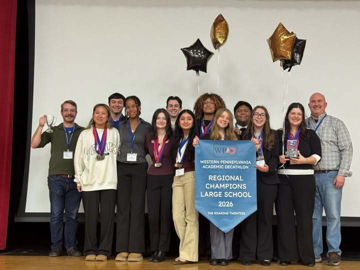 Students and adults standing on stage and holding a banner.