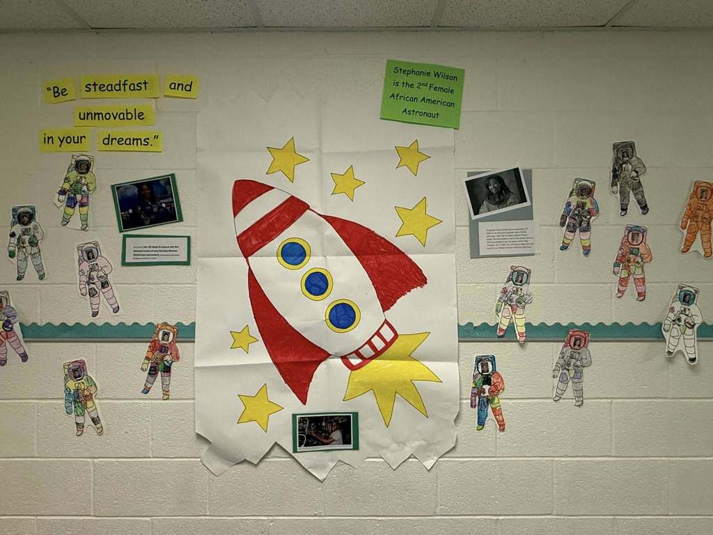 A wall that has a rocket and astronauts around it on a wall.