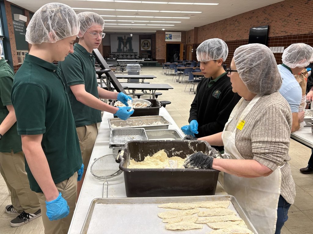 Volunteers breading fish filets and onion rings.