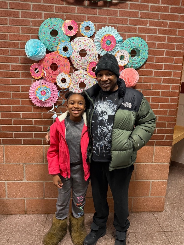 A kid standing with a male adult.