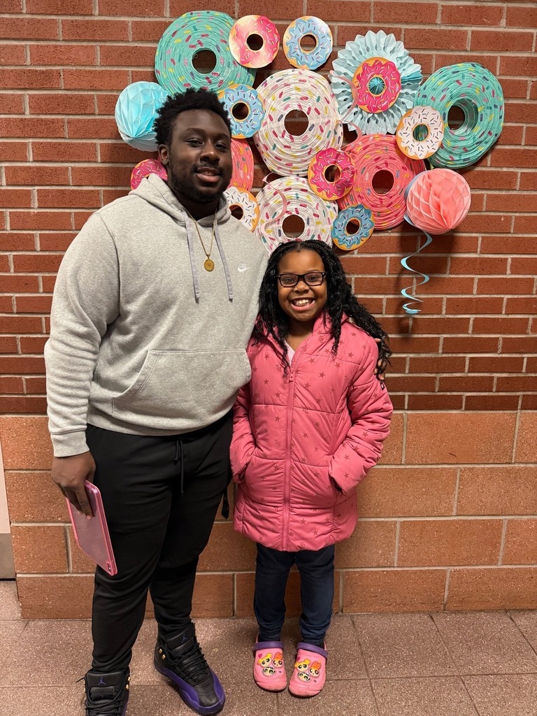 A kid standing with a male adult.