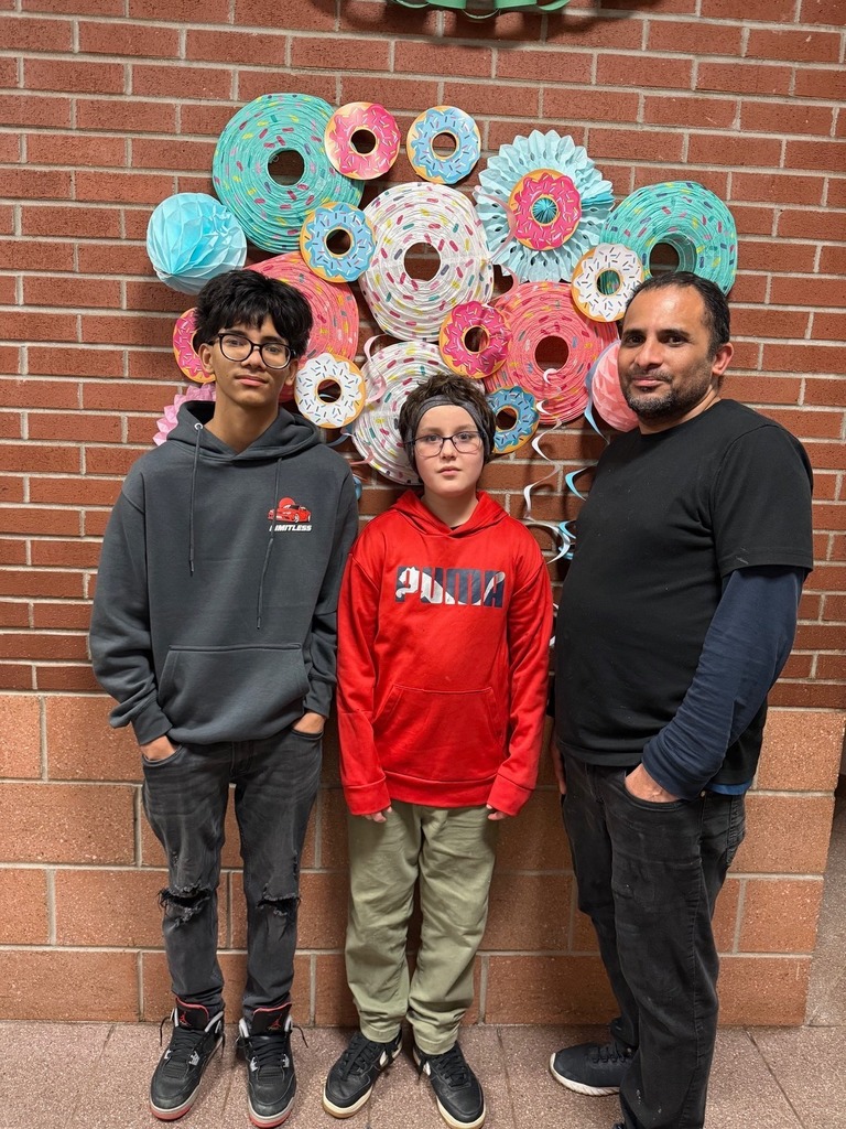 Two kids standing with a male adult.