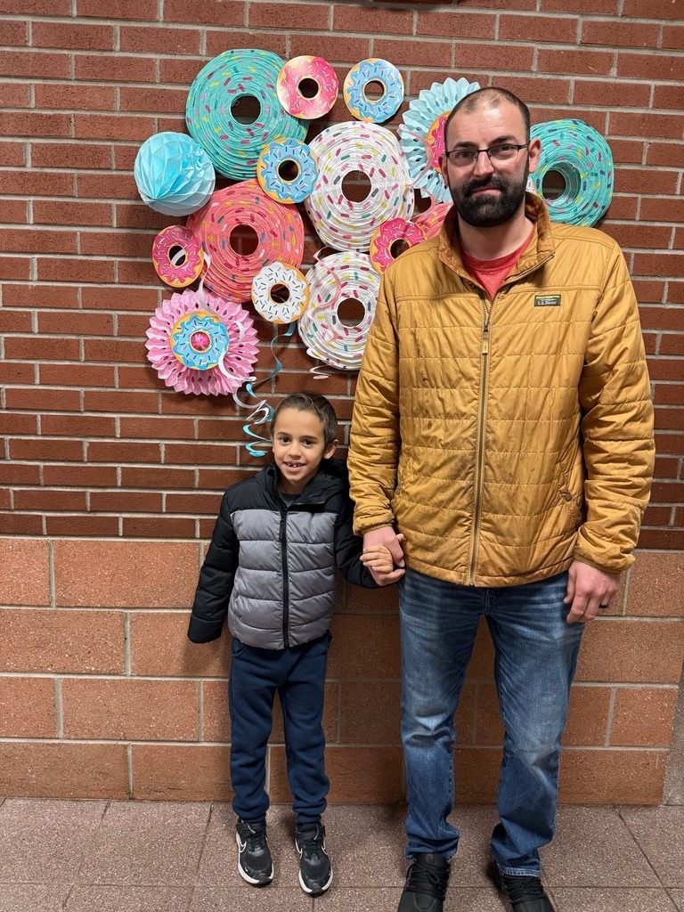 A kid standing with a male adult.