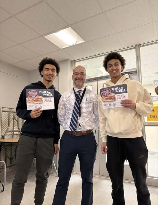 Two young males standing next to a man in a striped tie.