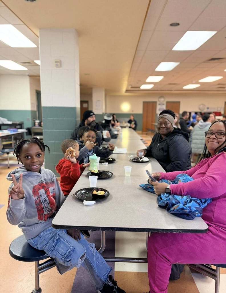 Students with their family eating breakfast at school.