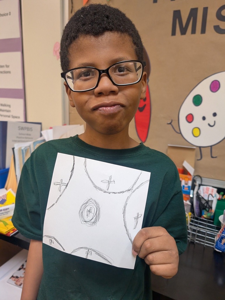 Young boy holding his drawing he created. 