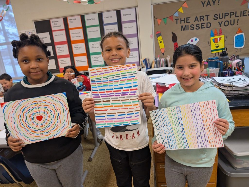 Students holding their colorful artwork they created. 