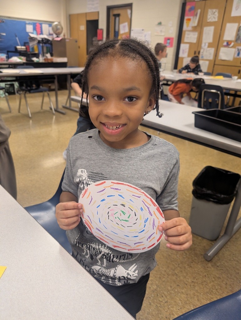 A young student holding their colorful art they created. 