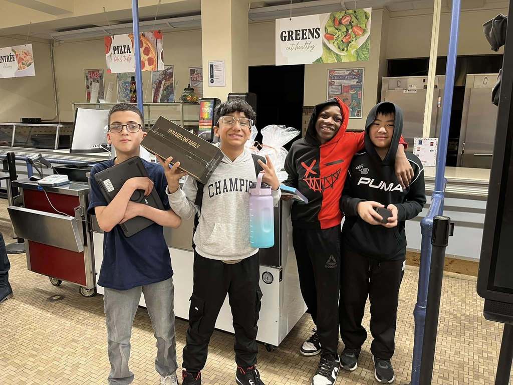 Students smiling and holding various items in their hands.