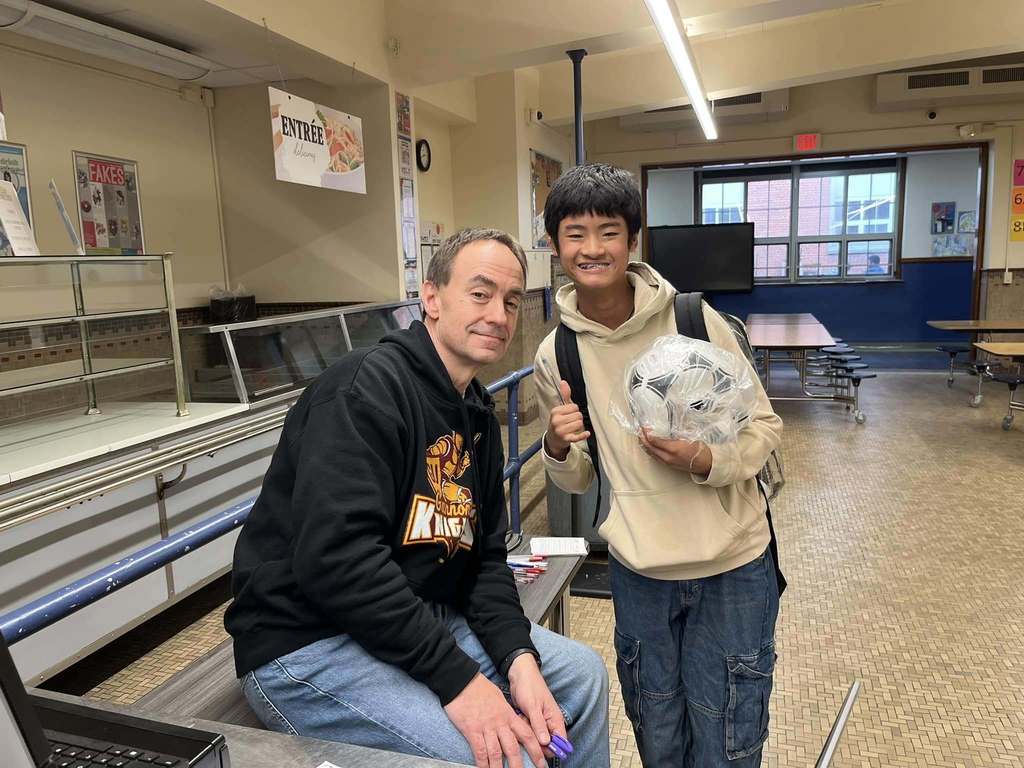 A student smiling next to a teacher.