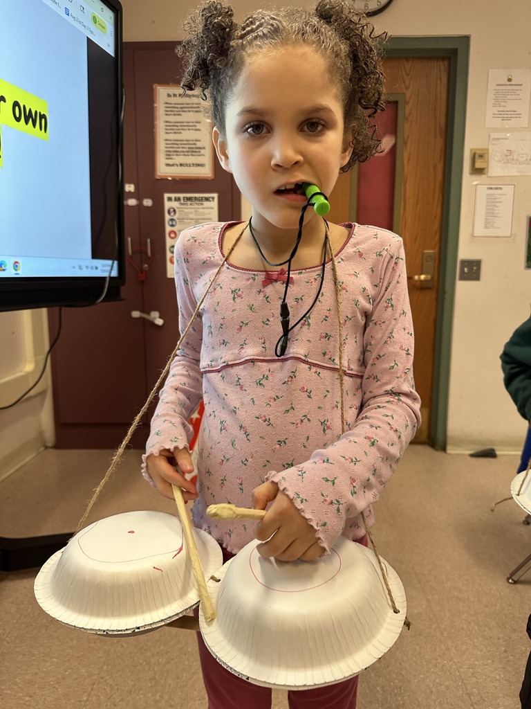 Student holding drums she crafted from items in the classroom.