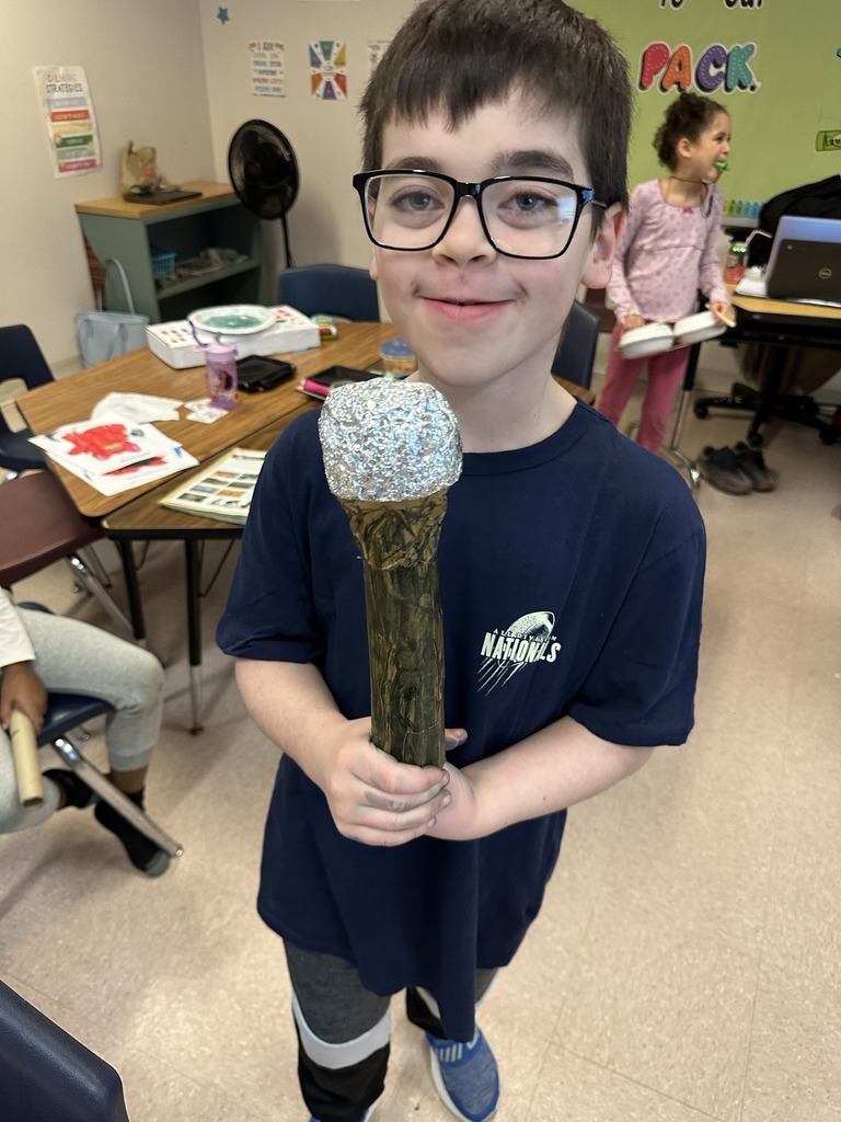 Student holding a microphone he crafted from items in the classroom.